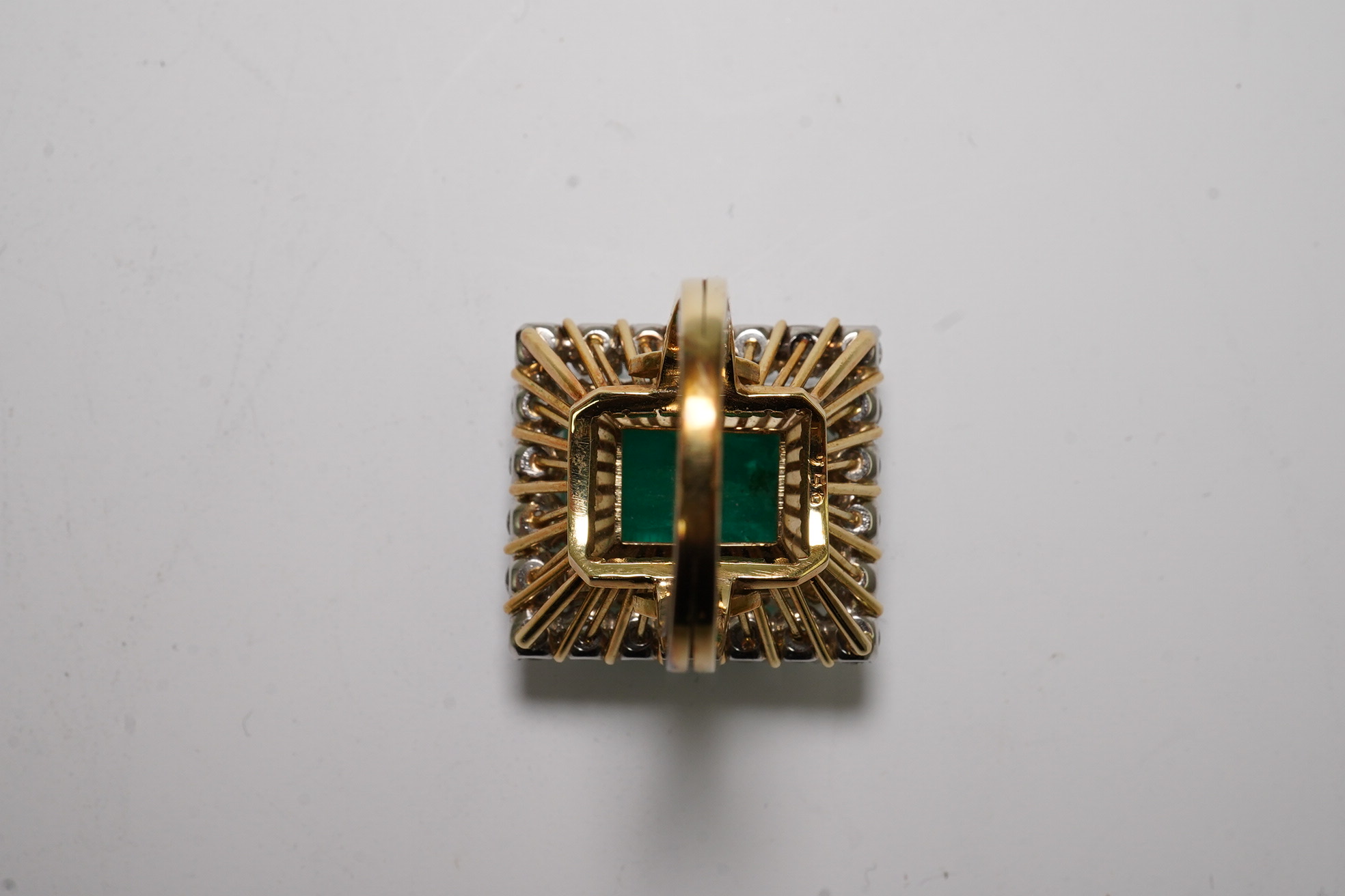 A Stern 18ct white and yellow gold, emerald and diamond dress ring, the central green emerald cut emerald approximately 8.0ct and surrounded by twenty two circular cut diamonds, approximately 2.7ct total